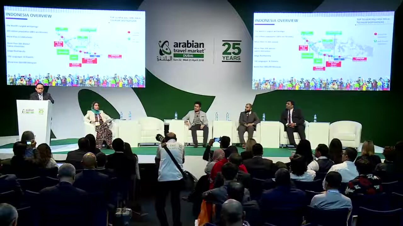 A full audience seated in front of the main stage panel at Arabian Travel Market in Dubai, with the event branding on the screens behind the panellists