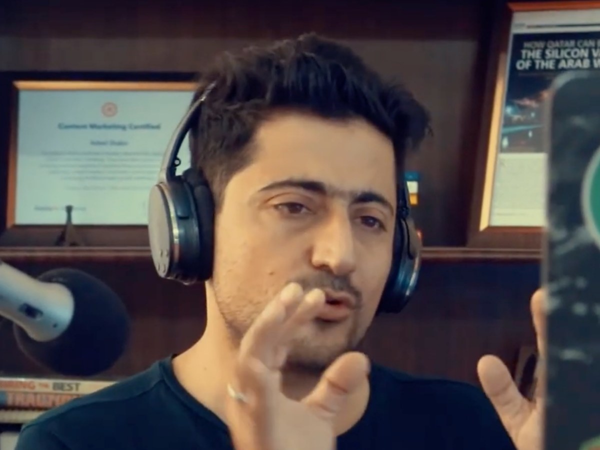 Syed Irfan Ajmal recording an episode at the microphone, wearing headphones in his studio